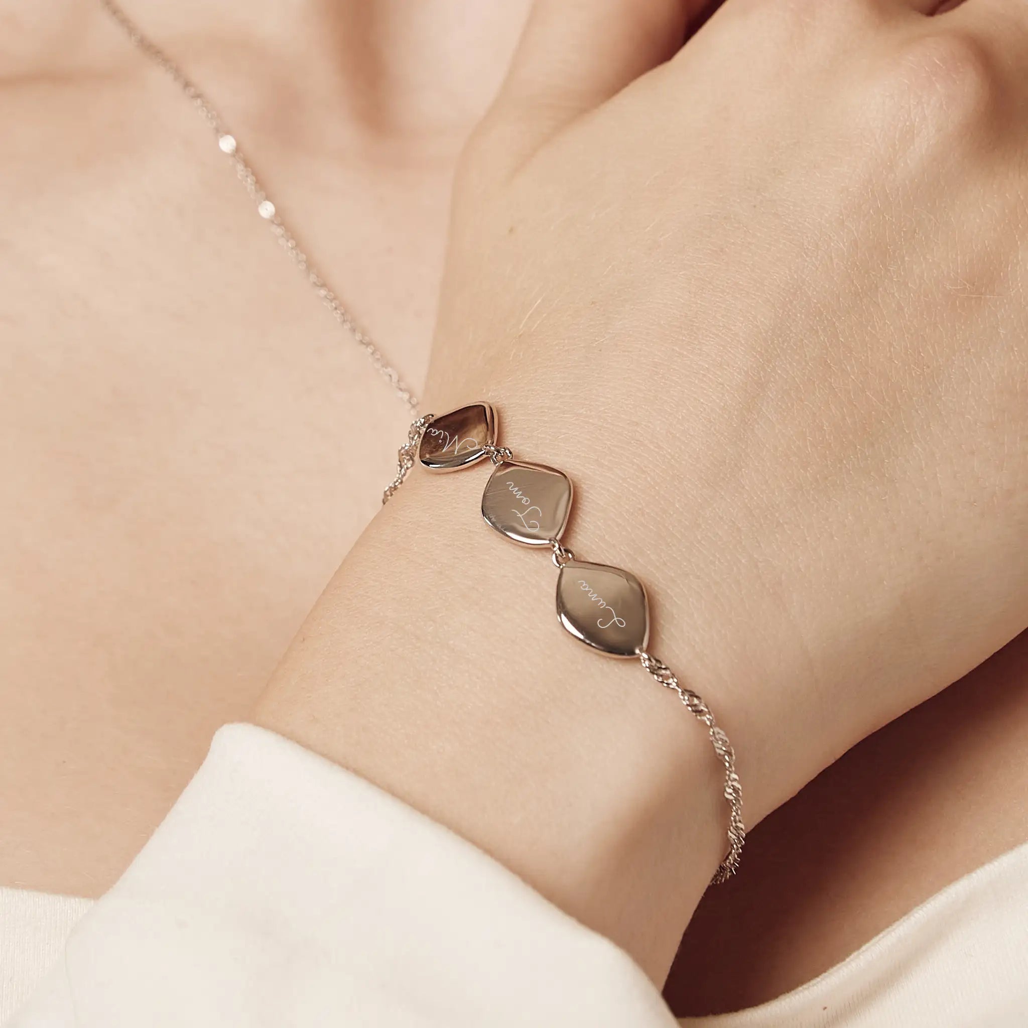 Sterling silver family name bracelet with three organic pebbles, handcrafted in the UK, showing personalized name engravings