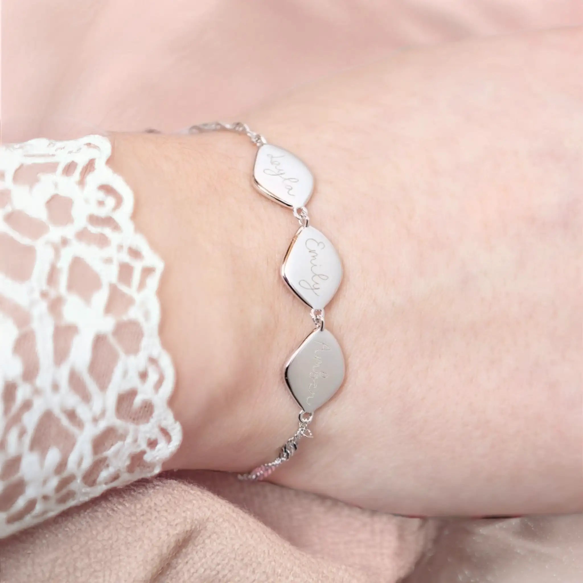 Close-up of recycled sterling silver family names bracelet showing precise laser engraving on organic pebble charms