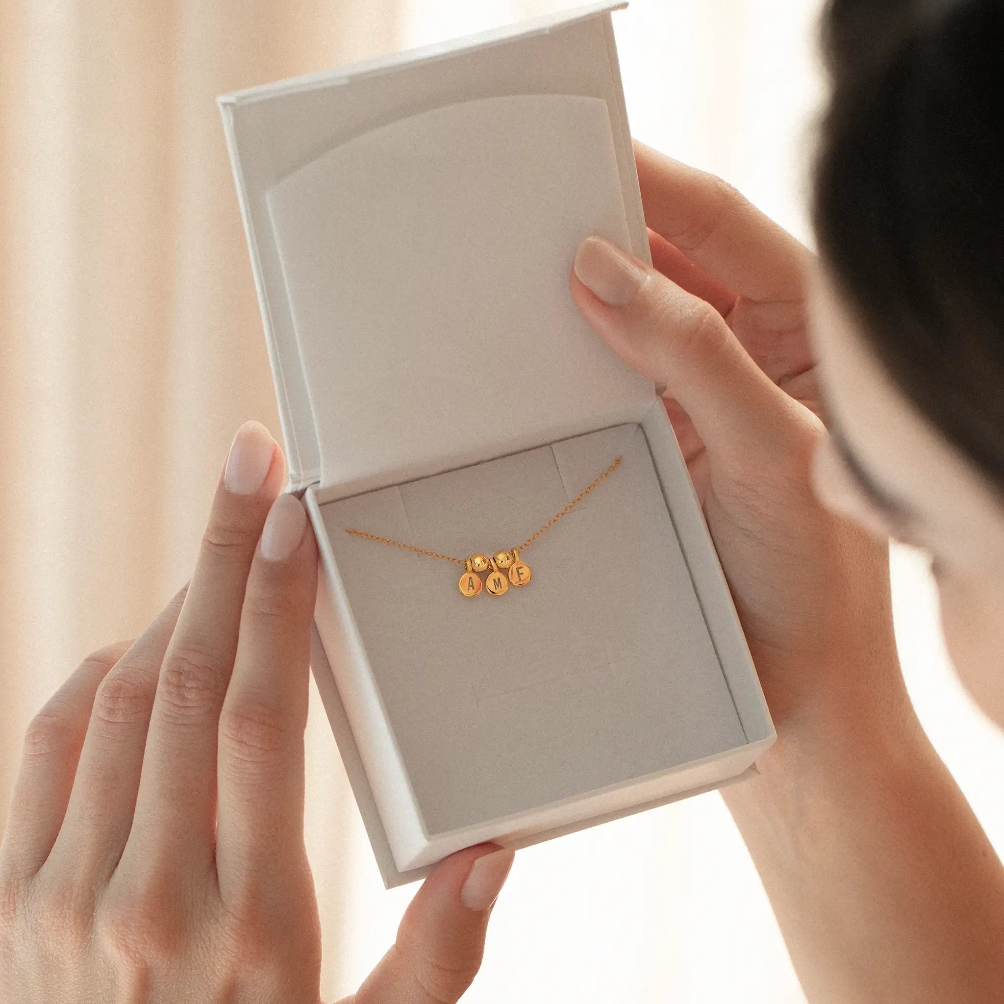Precious metal engraved necklace with triple initials, showcasing minimal design in gold finish